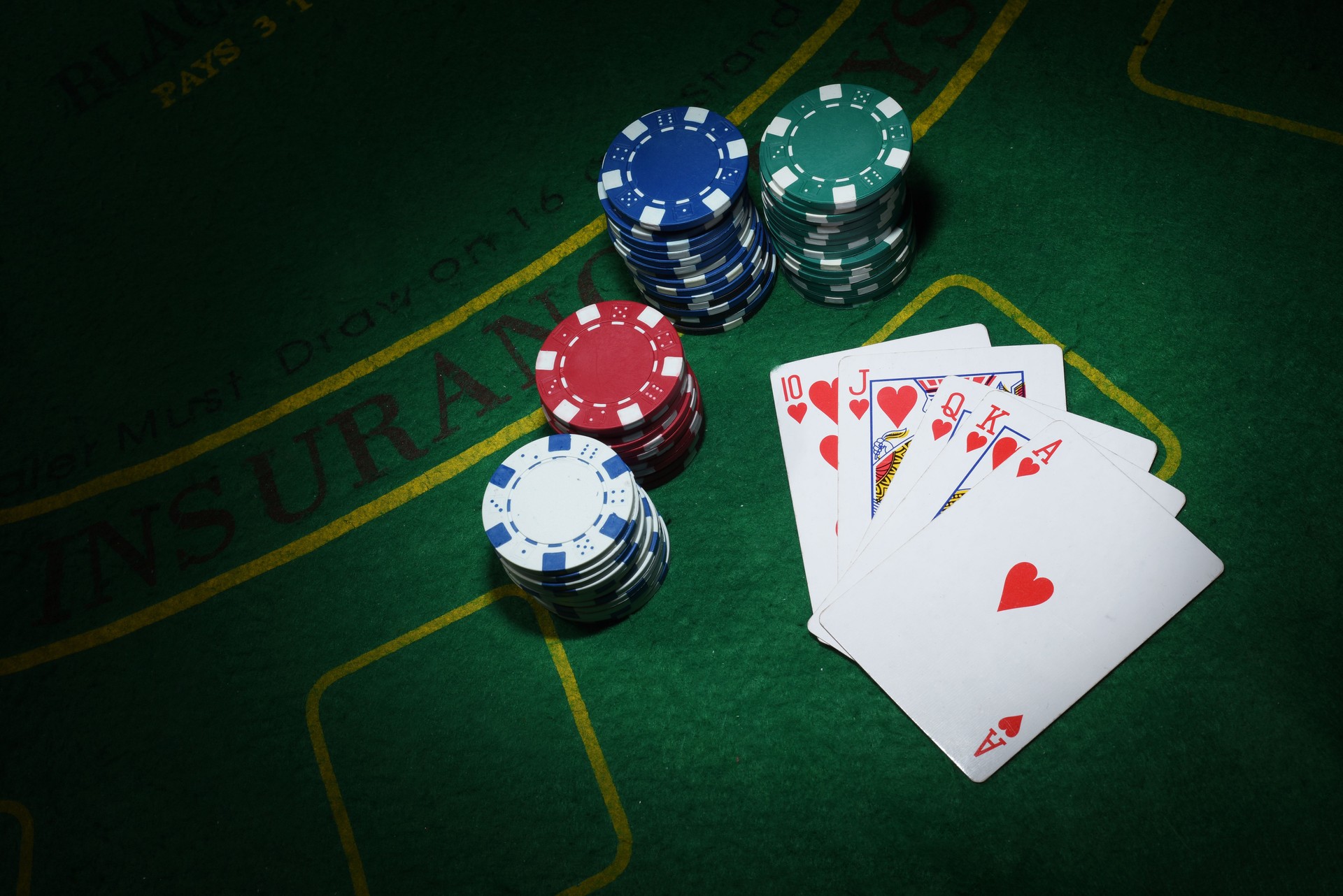 Cards and chips for poker on green table, top view