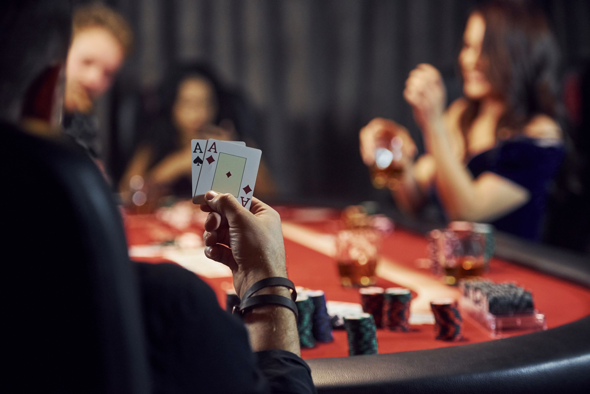 Guy have pair of aces. Group of elegant young people that playing poker in casino together