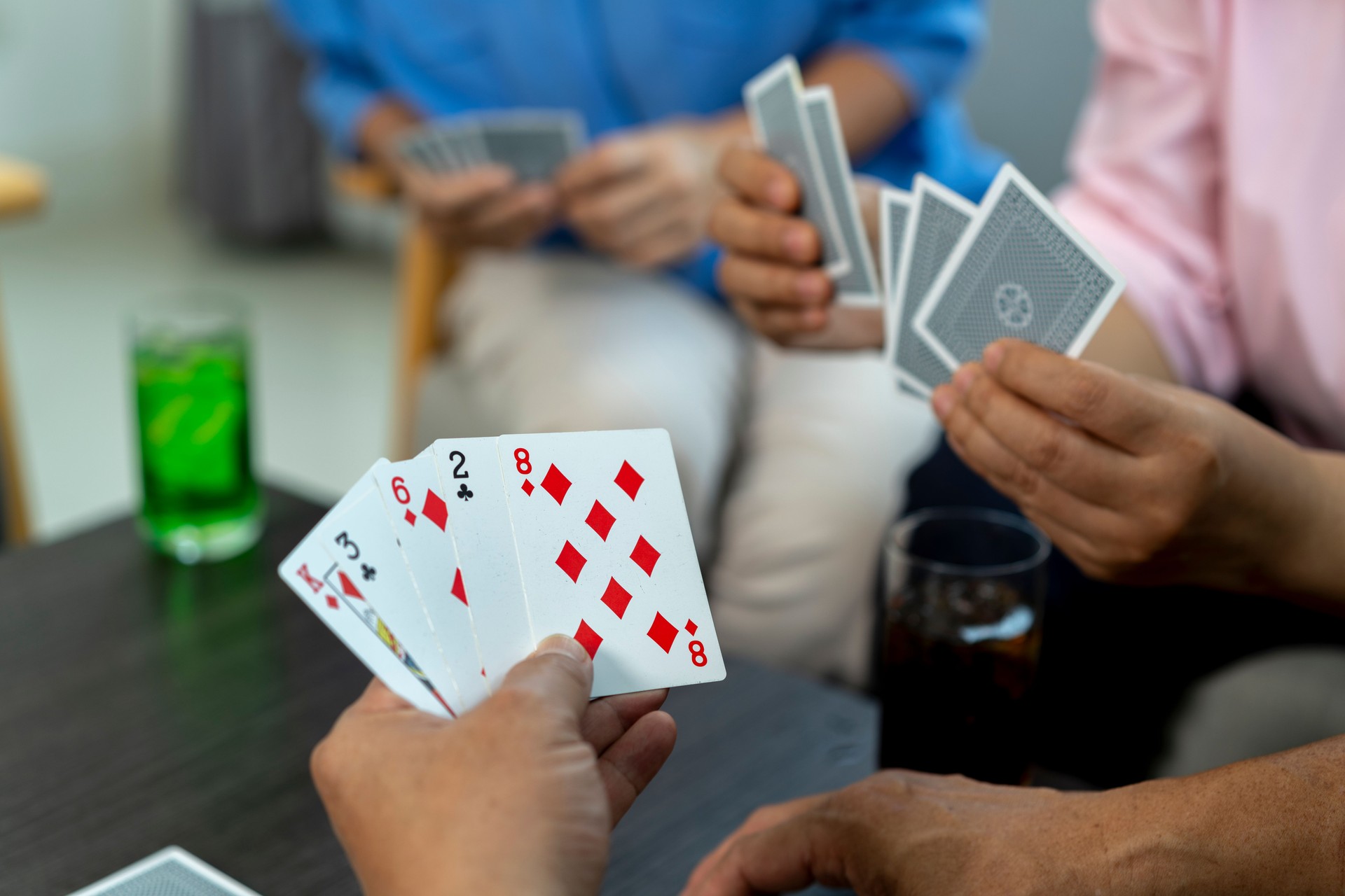 Retired Asian Friends Socializing and Playing Cards in Bright Living Room